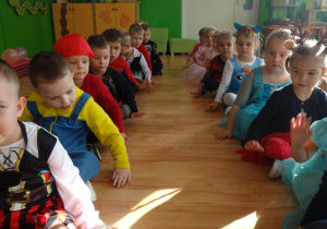 Dzieci siedzą na podłodze w bajkowych strojach
